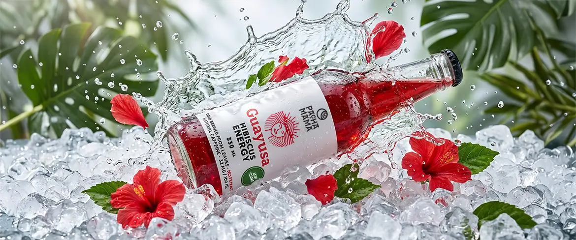 Guayusa Pachamama Cold Brew palack zúzott jégen, hibiszkuszvirágokkal.